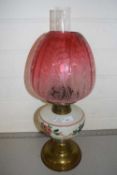 Brass based oil lamp with cranberry tinted shade