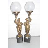 A pair of table lamps formed as figures holding torchairs set on polished stone bases