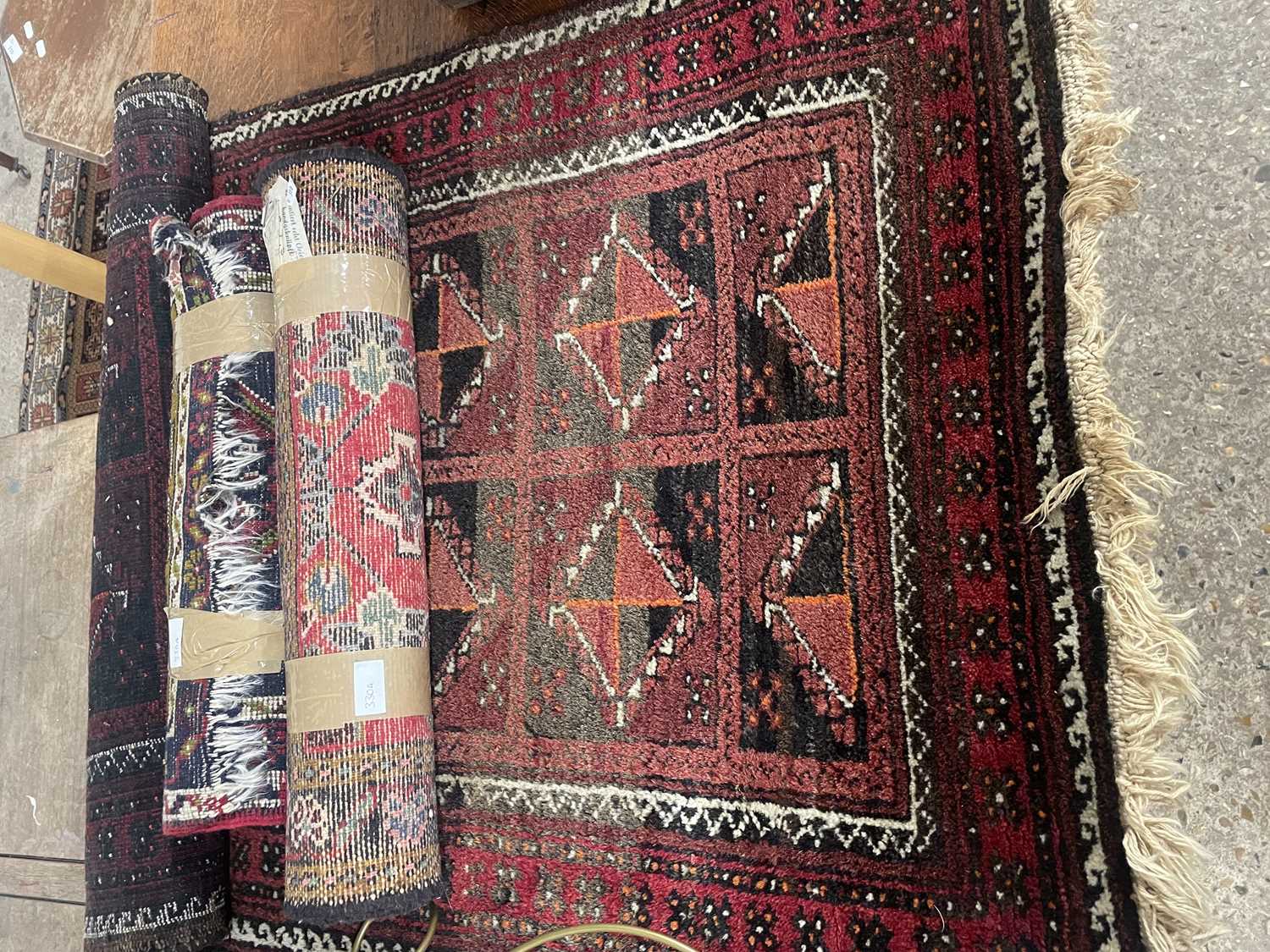 Small Middle Eastern wool floor rug decorated with central lozenges on a mainly red background