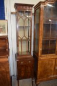 An unusual mahogany display cabinet of extremely narrow form with single glazed door over a base