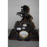 A French black slate and marble mounted mantel clock with applied metal marley horse detail