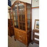 An early 20th Century walnut veneered arch top display cabinet with cupboard base, 197cm wide