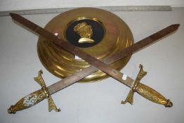 Two decorative swords together with a brass wall plaque