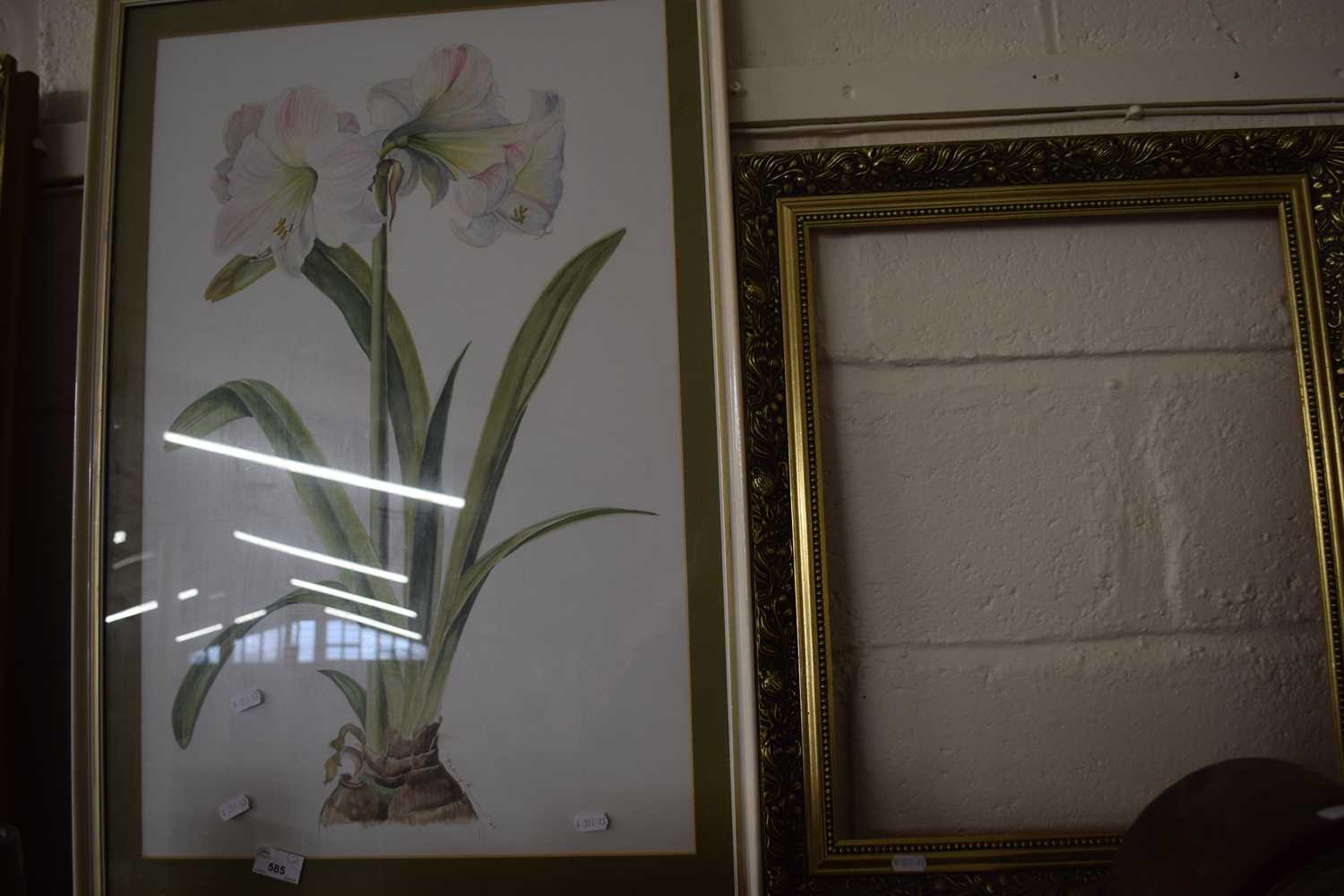 A picture of lilies together with an empty gilt frame