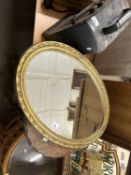 An oval wall mirror in gilt frame