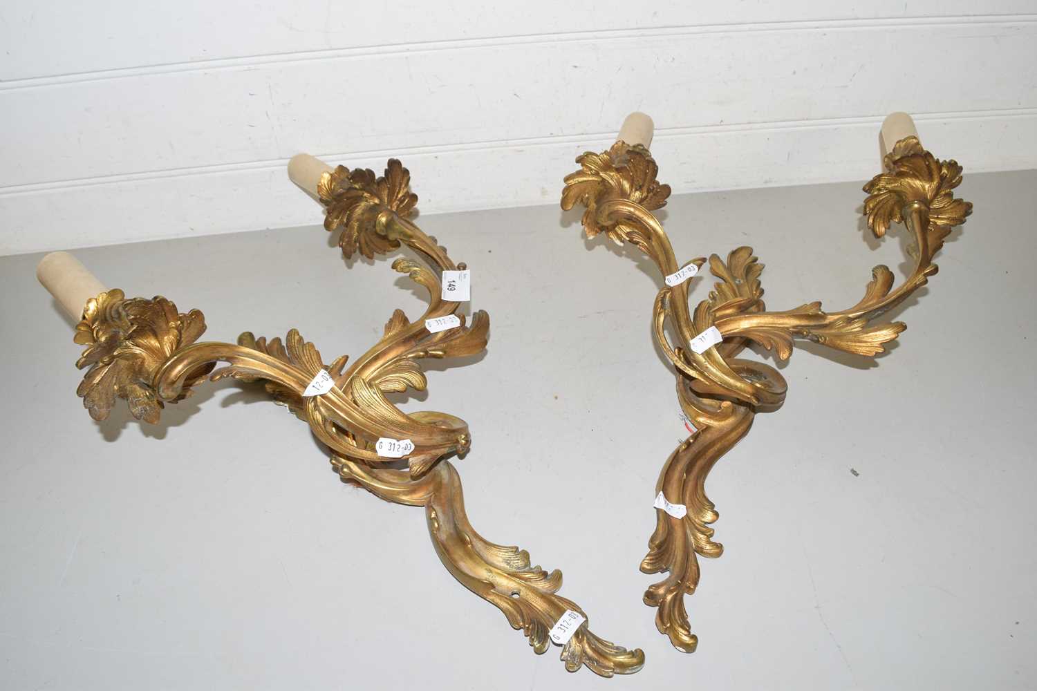 A pair of brass foliate formed twin light wall sconces