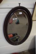Edwardian oval bevelled wall mirror in mahogany frame with carved detail