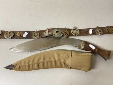 Mixed Lot: A leather belt mounted with various military cap badges together with a Kukri type knife