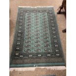 Middle Eastern floor rug set with central panel of lozenges on a green background, 187 x 123 cm