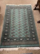 Middle Eastern floor rug set with central panel of lozenges on a green background, 187 x 123 cm