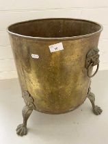 Large brass cylindrical three footed jardiniere with lion mask handles