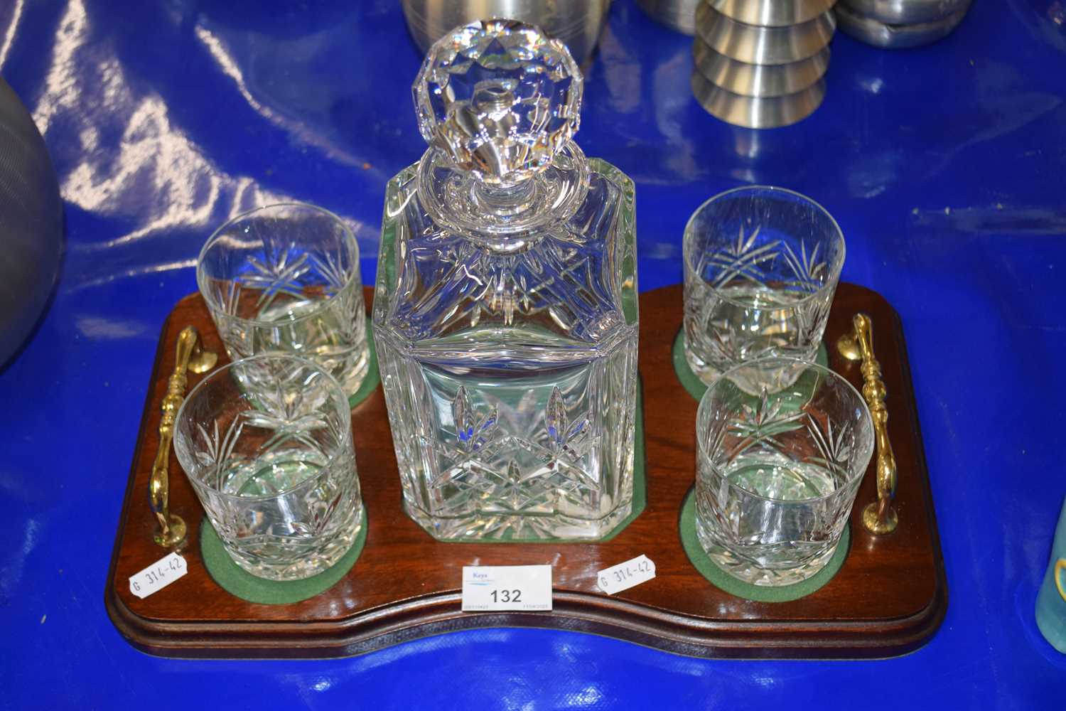 Crystal glass decanter with four accompanying tumblers and a polished wooden stand