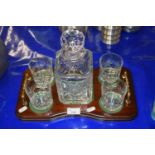 Crystal glass decanter with four accompanying tumblers and a polished wooden stand