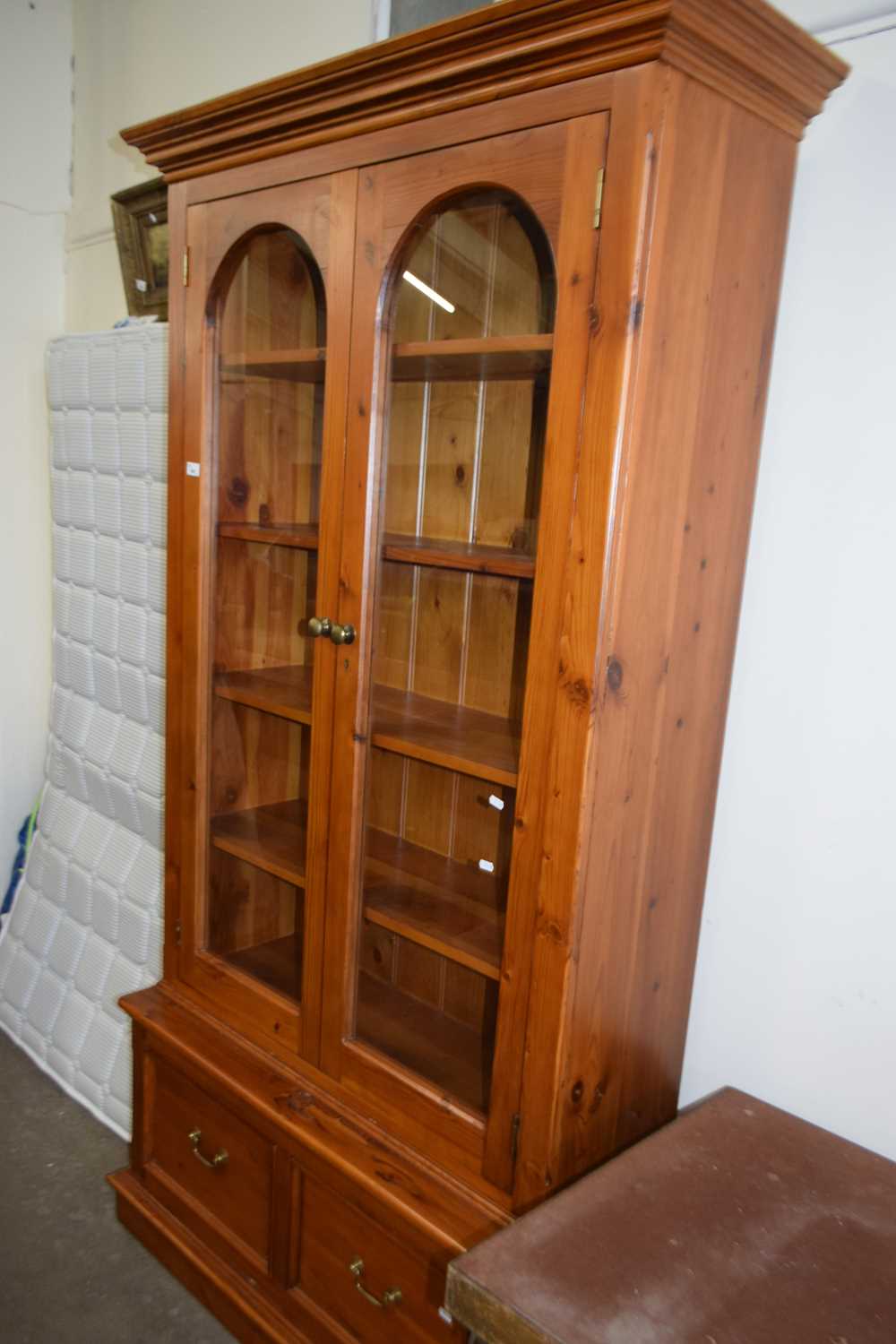 Pine wall cabinet with glazed arched doors, shelves within and two drawers below