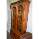 Pine wall cabinet with glazed arched doors, shelves within and two drawers below