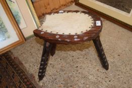 A small three legged stool with horseshoe shaped top