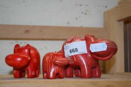 Three red hard stone carved hippos