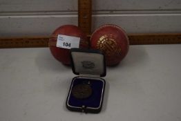 1924 cricket medal together with two vintage cricket balls