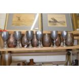 Six copper finish barrel shaped and embossed tankards together with six white metal goblets