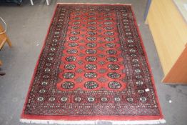 Modern wool floor rug decorated with geometric design on a red background