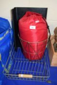 A red sleeping bag and a modern brass waste paper basket