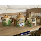 Novelty teapot in the shape of a cottage with bumble bees together with a matching milk jug and