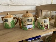 Novelty teapot in the shape of a cottage with bumble bees together with a matching milk jug and