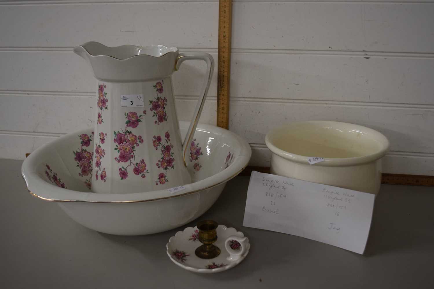 Wash jug and bowl decorated with pink flowers together with a matching chamber stick and a cream