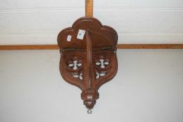 A wall mounted wooden gothic style bracket with hinged support and shelf