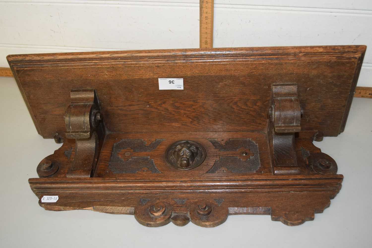 A wooden wall shelf with lion mask decoration