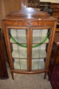 An Edwardian bow fronted display cabinet with lead glazed doors with green glass arched feature,