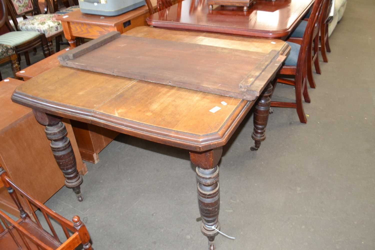 An oak extending dining table on turned legs and casters with extra leaf