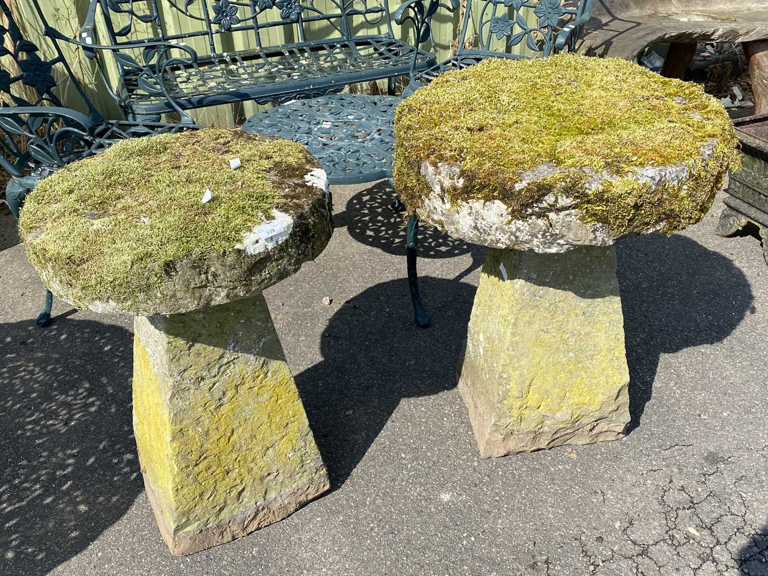 Two staddle stones of slightly differing design, both with heavily moss covered tops, one top