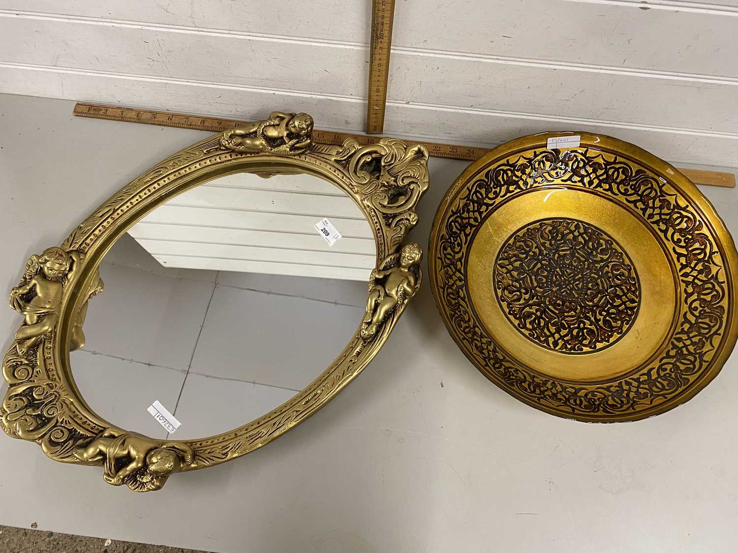 Oval wall mirror in plaster work frame together with a lacquered finish metal fruit bowl