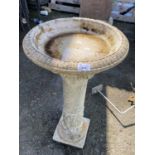 A reconstituted stone bird bath on pedestal base