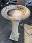 A reconstituted stone bird bath on pedestal base