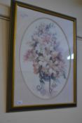An oval print of lilies and flowers i a vase, framed and glazed
