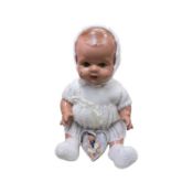 A vintage composite baby doll with green flirty eyes, in white knitted outfit, together with a