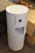 A pair of white round side tables with two tier shelves and sliding doors