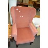 An apricot coloured upholstered wing back easy chair