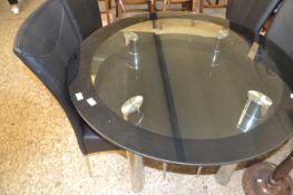Modern circular glass top dining table and four accompanying black upholstered chairs