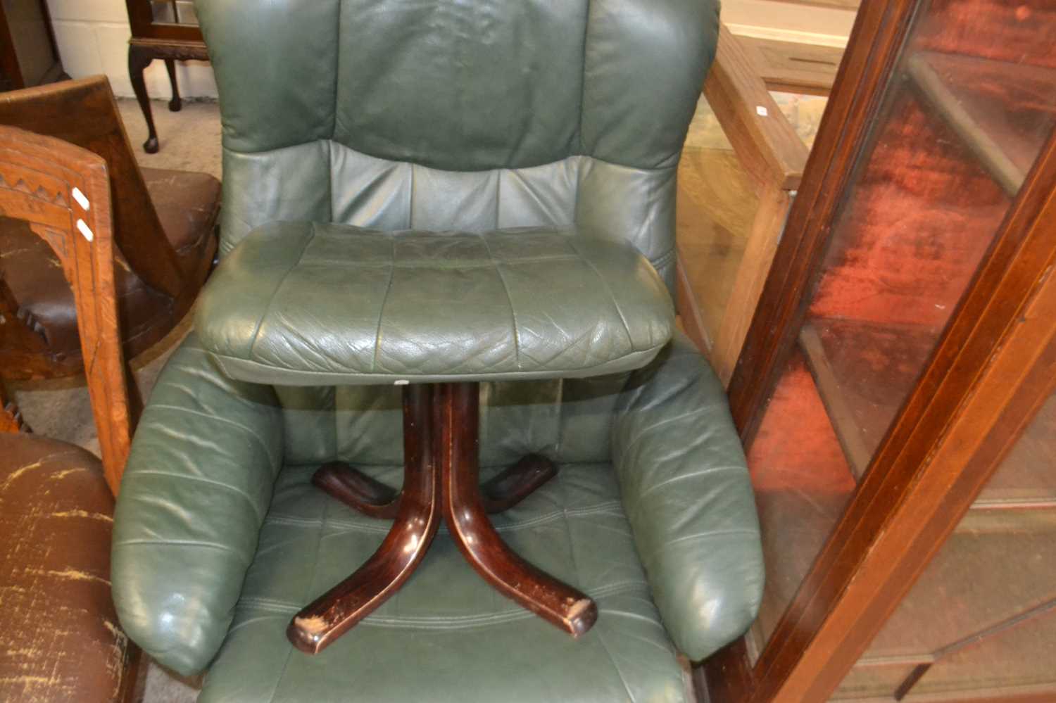 Green leather upholstered swing armchair and accompanying stool