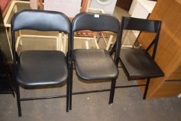 A pair of black folding chairs and another similr (3)