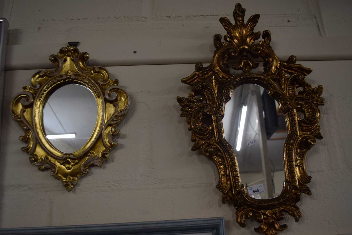 An ornate gilt framed wall mirror together with another smaller similar oval example (2)