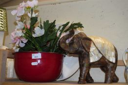 Red metal bowl together with terracotta tea cannister, artificial flowers and a carved wooded with