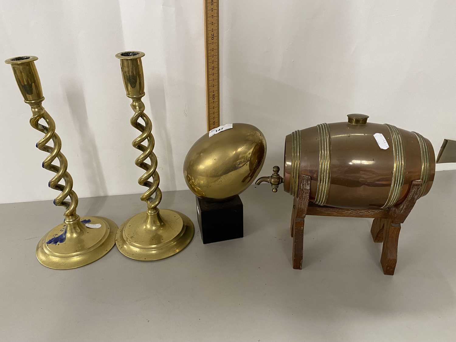 Pair of brass barley twist candlesticks, a brass egg and a small coppery spirit barrel with stand