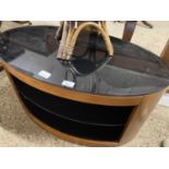 A oval black glass topped television stand with internal shelves