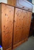 Modern pine wardrobe with three doors, two base drawers and a cupboard to the top together with a
