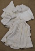 A mixed quantity of linens to include a white cotton christening gown, an oval crochet lace