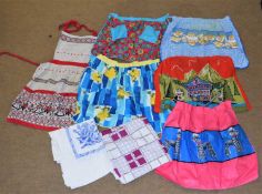 A quantity of vintage cotton printed hostess / cocktail aprons and printed tablecloths